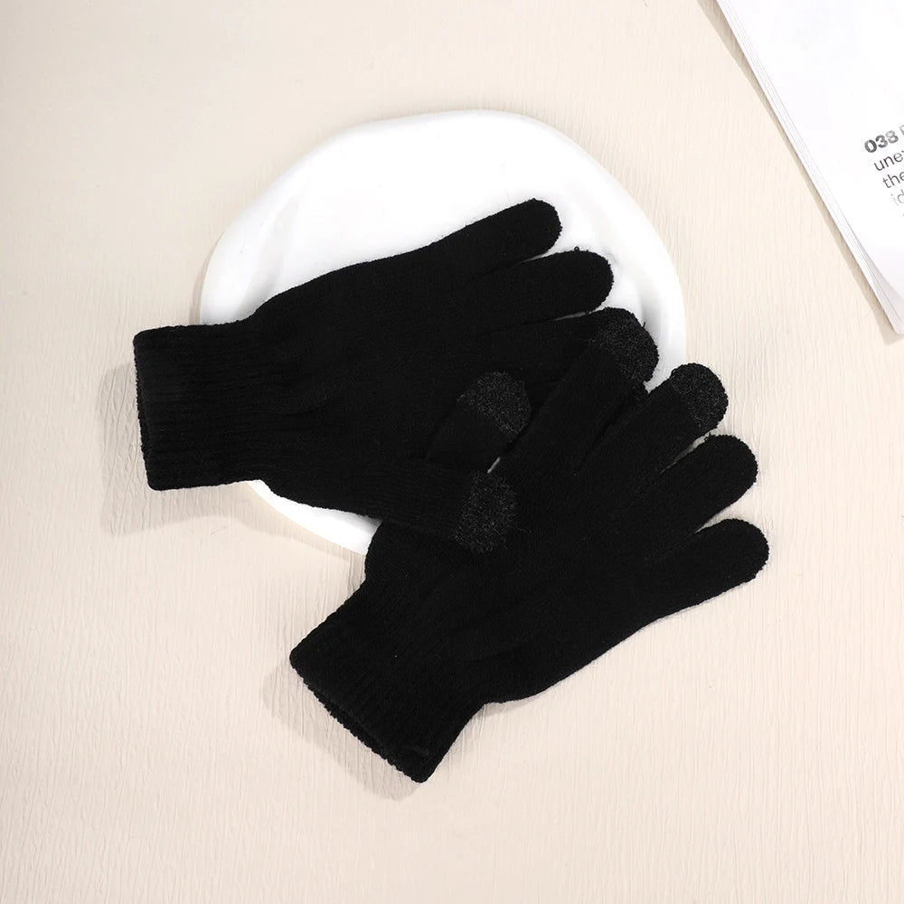 A pair of black cozy knit touch screen gloves resting on a white plate.