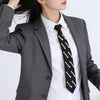 Elegant black tie adorned with white pearls worn under a gray blazer.