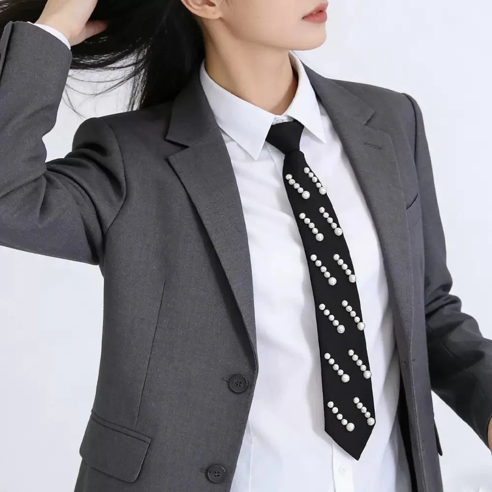 Elegant black tie adorned with white pearls worn under a gray blazer.