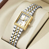 A gold-toned minimalist quartz wristwatch with a silver and gold striped metal bracelet resting on a beige leather surface.