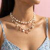 A close-up of a boho shell starfish necklace with pearl and gold accents worn around the neck.