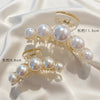A pair of simulated pearl hair claws, one measuring 11.5cm and the other 6.8cm, displayed on a white satin fabric.