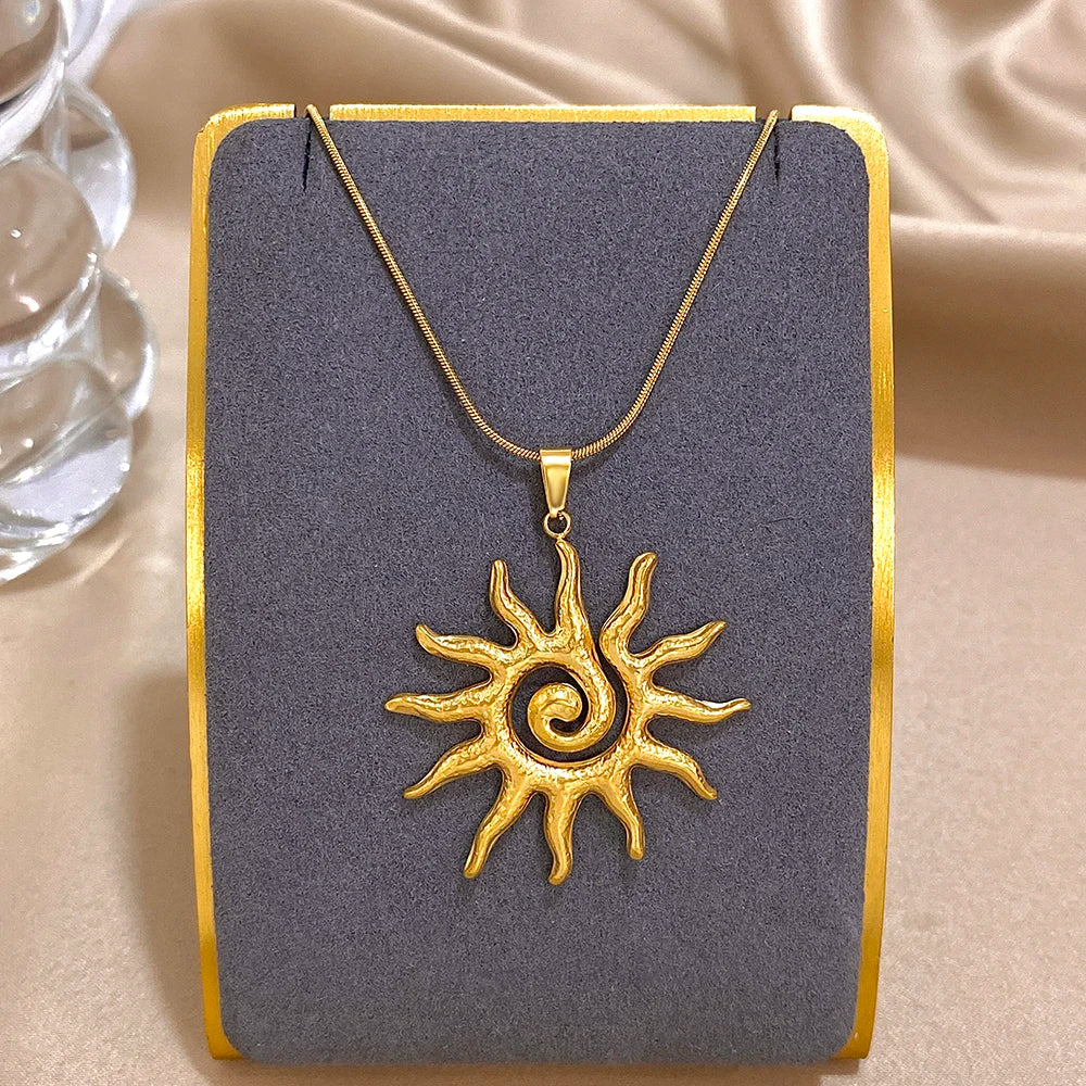 Collier fleur de soleil en spirale plaqué or, présenté sur une carte gris foncé.