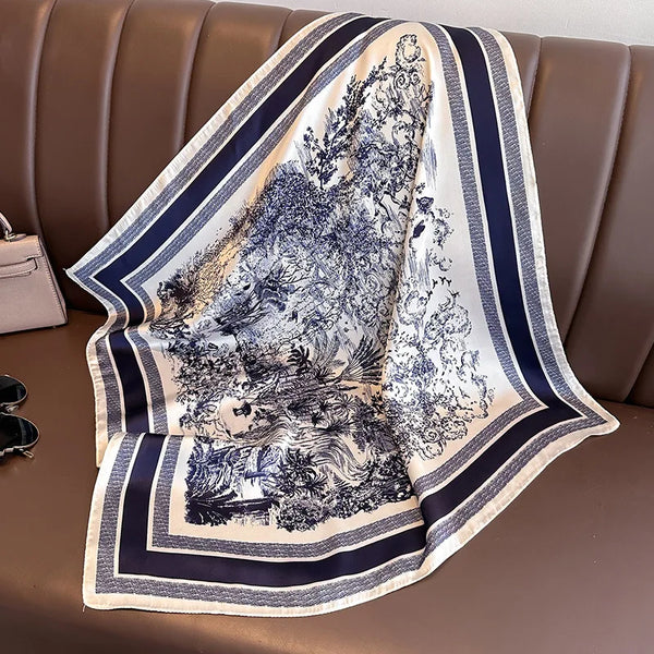 A silk scarf with a blue and white floral print draped over a brown leather sofa.