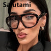 A woman wearing black vintage gradient leopard print sunglasses indoors.