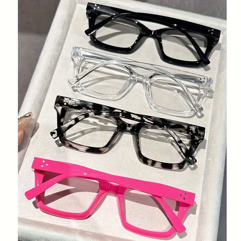 A display of five pairs of reading glasses in various styles and colors including black, clear, tortoiseshell, and pink.