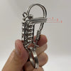 Un porte-clés mécanique en acier inoxydable avec une clé et un fermoir décoratif, tenu dans une main.