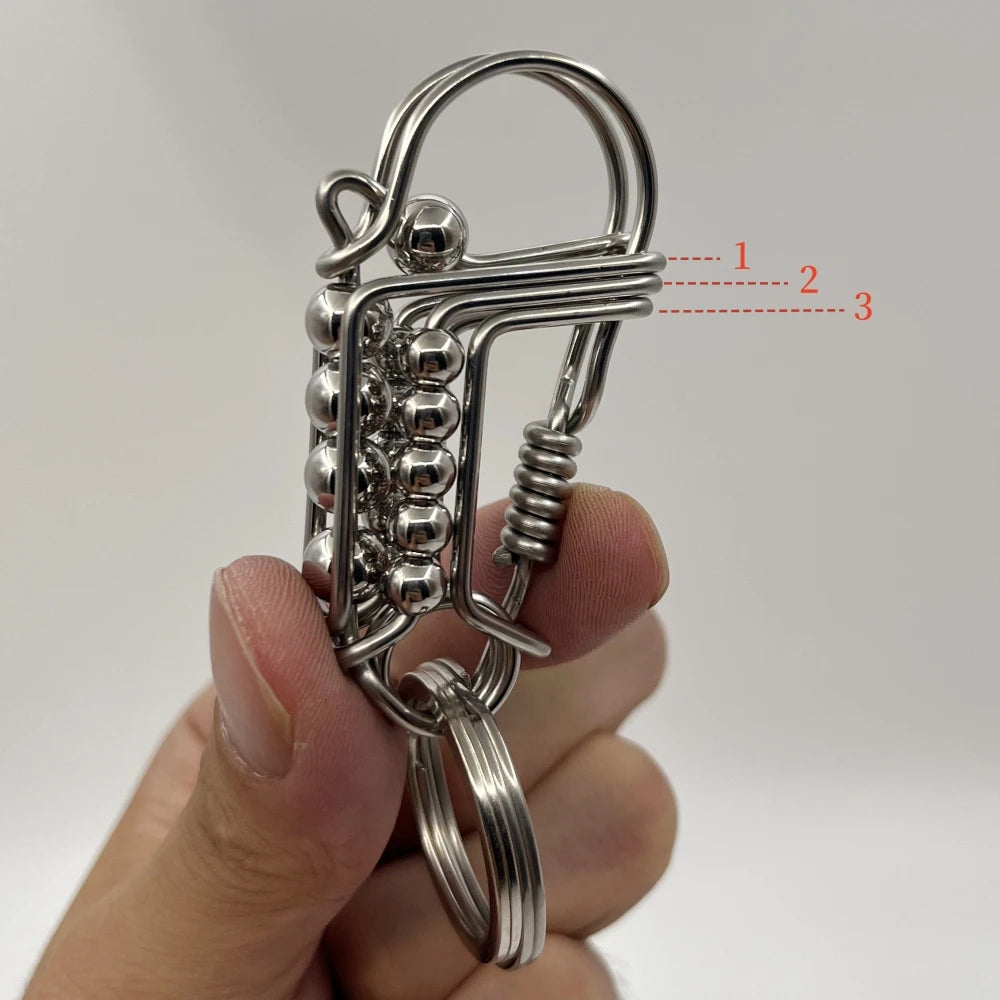 Un porte-clés mécanique en acier inoxydable avec une clé et un fermoir décoratif, tenu dans une main.