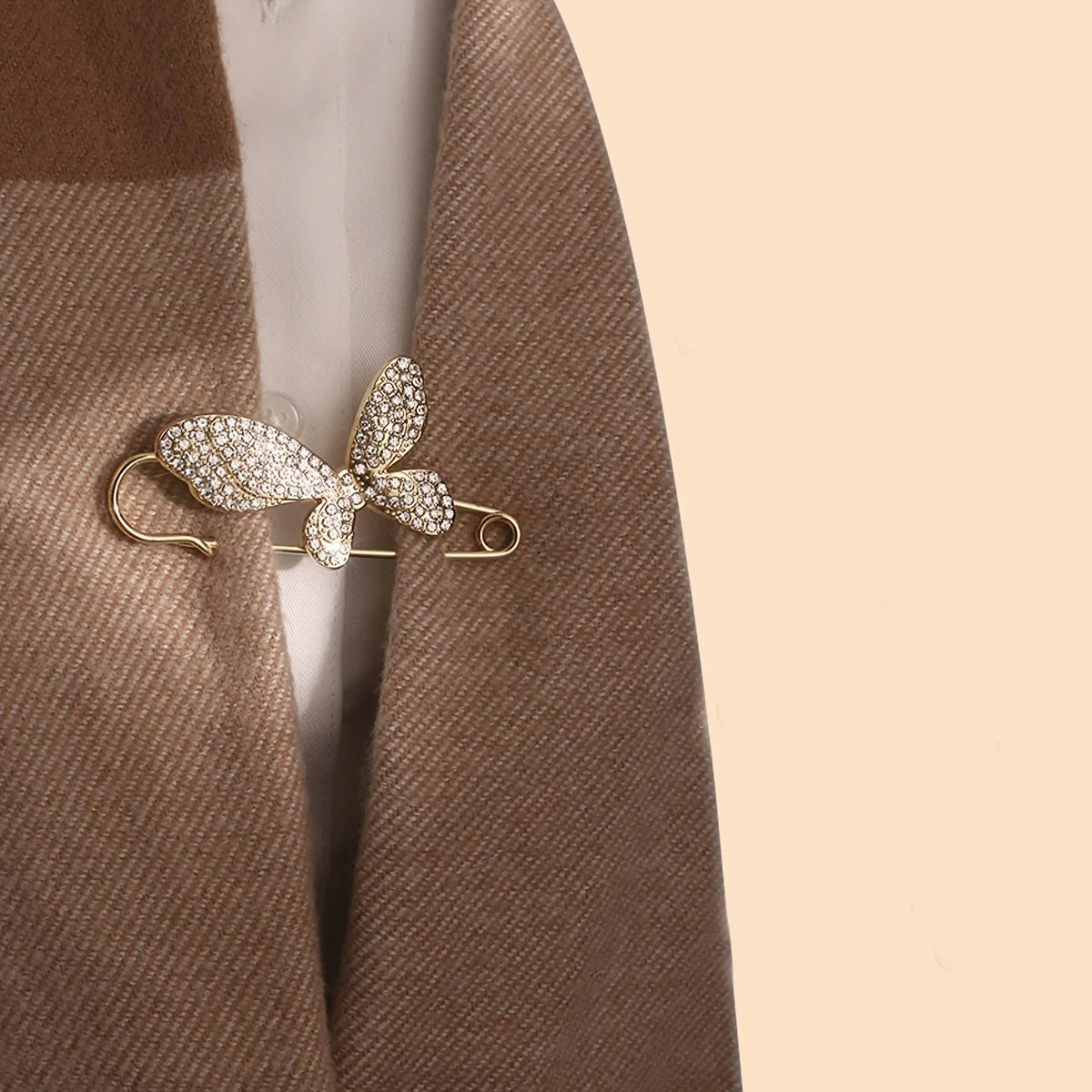 Glitzernder blumiger Modebrosche-Gürtelverschluss aus goldfarbenem Metall auf braunem Tweed