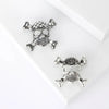 Broches de calavera con diamantes de plata sobre fondo blanco.
