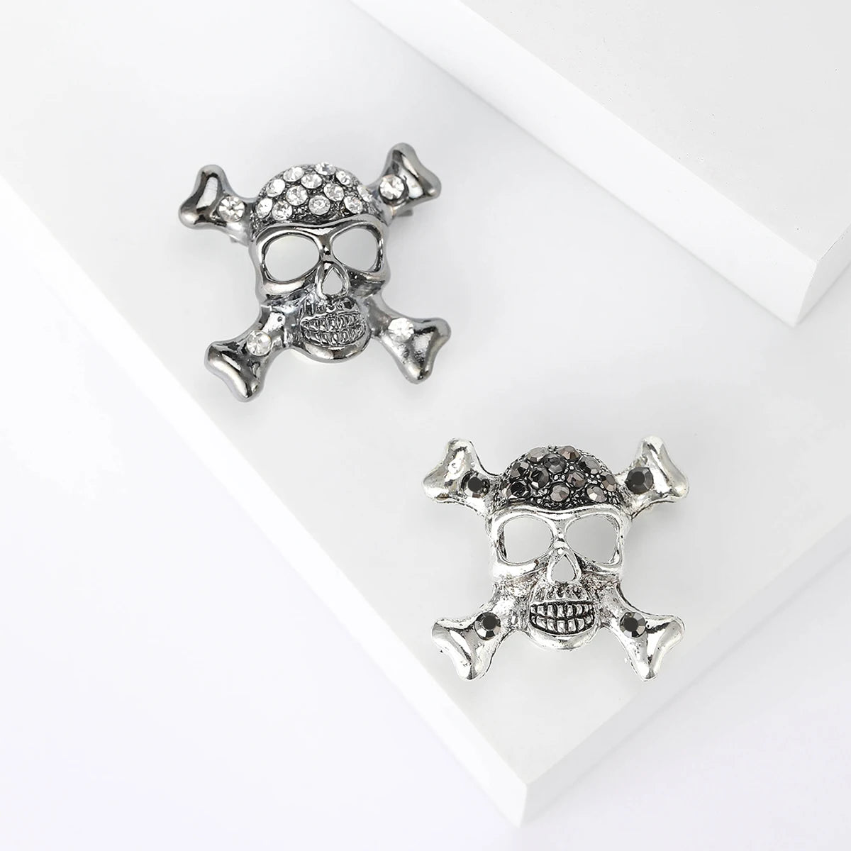 Broches de calavera con diamantes de plata sobre fondo blanco.