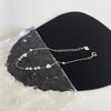 Sterling silver double heart charm bracelet displayed on a black surface next to a piece of rough white stone.