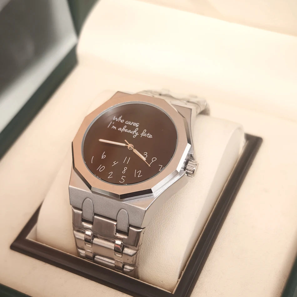 A stainless steel watch with a black dial featuring the slogan Who cares I'm already late, displayed in a presentation box.