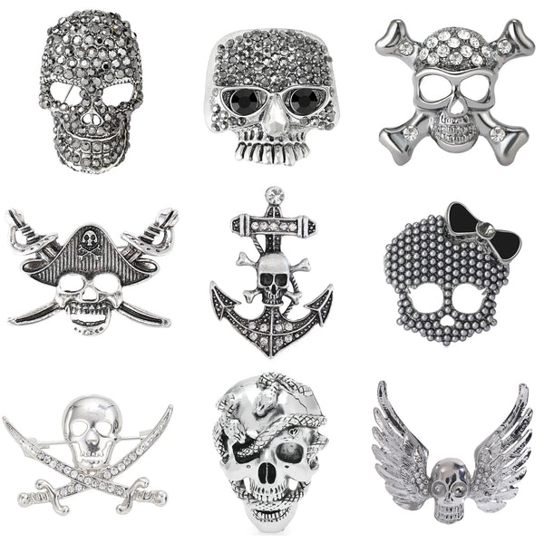 A collection of silver and rhinestone skull brooches featuring various designs including skulls, anchors, and wings.