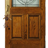 A wooden door with a glass panel and a brass hardware featuring a Saint Benedict protection charm set.