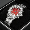 A silver watch with dragon scale design and a red dial is displayed in a black velvet box.
