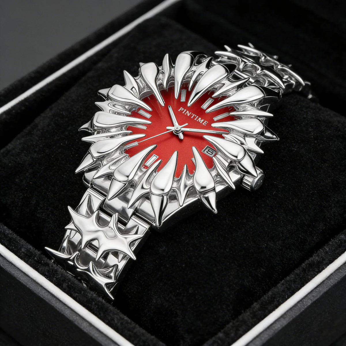 Silver watch with dragon scale design and red dial displayed in a black velvet box.