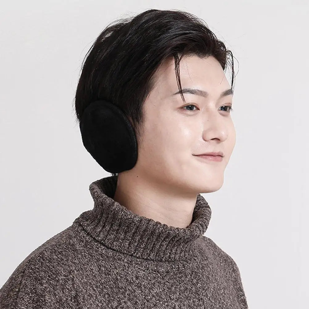 A close-up profile shot of a person wearing black plush winter earmuffs and a gray turtleneck sweater.