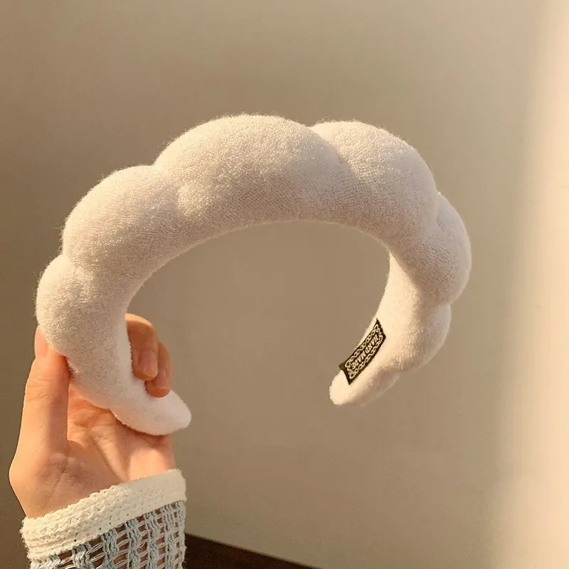 A hand holds a white cloud-shaped sponge headband for hair accessories.