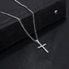 A silver stainless steel cross pendant necklace with a chain is displayed on a black surface.