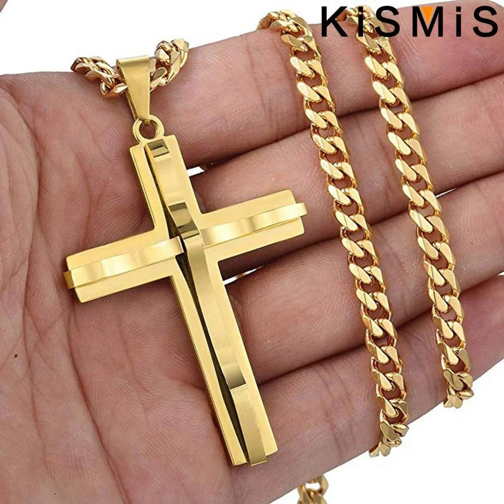 Colgante de cruz y pulsera de cadena de acero inoxidable color dorado exhibidos en una mano.