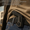 A tactical pistol keychain with a black holster is clipped onto the waist of a person wearing a denim shirt.