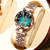 A close-up of an elegant stainless steel quartz ladies wristwatch with a teal dial and rose gold accents, resting on a cream-