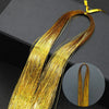 Golden rainbow glitter hair extensions strands laid out on a dark surface.