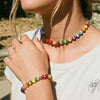 Nahaufnahme einer Frau mit einem Hals- und Armbandset aus farbigen UV-reaktiven Perlen.