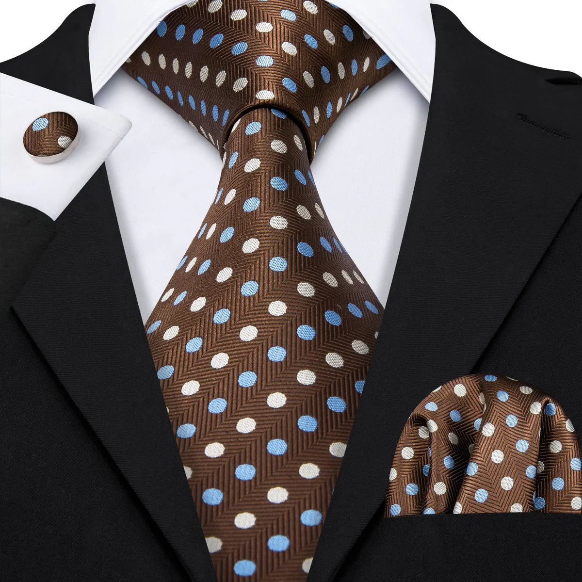 A close-up of a brown and blue patterned silk jacquard tie worn with a black suit jacket and white shirt.