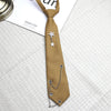 A tan necktie featuring a silver star pendant on a chain, displayed on a light gray fabric.