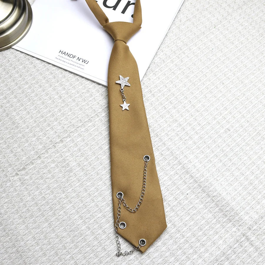 A tan necktie featuring a silver star pendant on a chain, displayed on a light gray fabric.