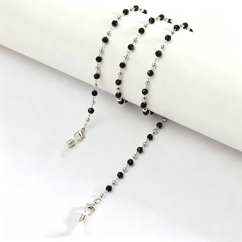 A delicate silver chain with black beads is displayed against a white background.