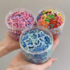 A hand holds three clear containers filled with colorful Y2K sweet star barrettes hair clips.