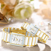 A pair of gold and white ceramic fashion wristwatches displayed on a light surface with soft floral background.