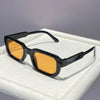 Black retro square sunglasses with orange tinted lenses resting on a white surface