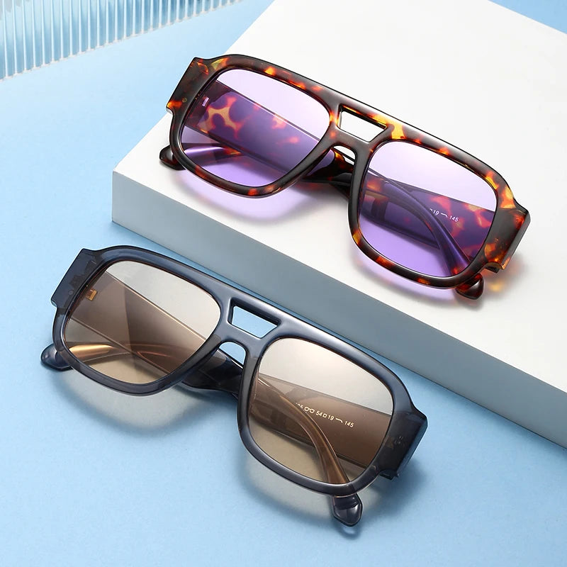 Paire de lunettes carrées vintage avec double pont posées sur une boîte blanche.