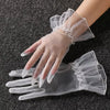Clear lace tulle finger gloves worn on a hand against a dark background.