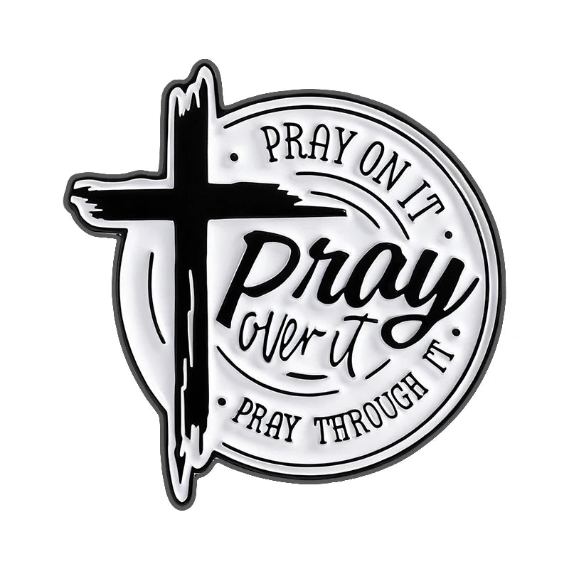 Broche émail noir et blanc avec une croix et le texte : Prie dessus, prie par-dessus, prie à travers.