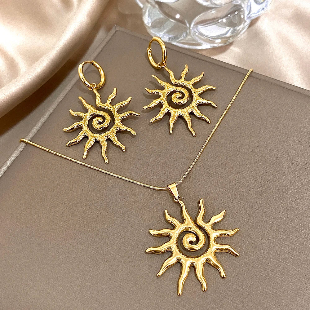 Collier fleur de soleil en spirale plaqué or avec chaîne et pendentif sur fond neutre.