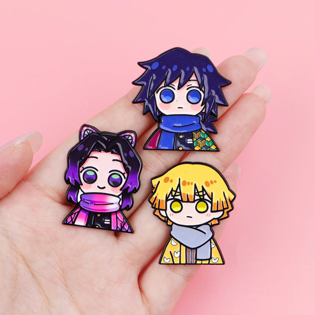 A hand holds a set of 12 anime enamel pin brooches featuring characters with dark hair and glowing eyes.