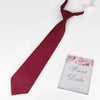 A maroon tie with a butterfly ribbon and a Save the Date card on a white background.