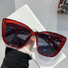 A pair of glossy red cat eye sunglasses resting on a white surface.