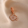 Rose gold heart pendant with a textured chain and small diamonds resting on a beige fabric.