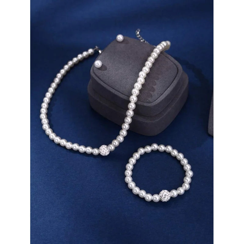 A set of four faux pearl necklaces and a storage pouch displayed on a dark blue velvet background.