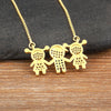 Collier pendentif ton or avec trois petites figurines stylisées en pierres CZ dorées.