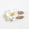 A white, pearlescent flower button cover with a gold center and a gold C-shaped clasp.