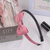 A pink grosgrain ribbon hair bow is displayed next to a box and a glass.