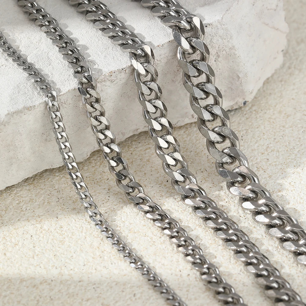 Silver stainless steel multi-chain anklets laid on a light surface.