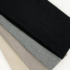 A set of four knitted hair bands in black, gray, beige, and light tan laid diagonally.